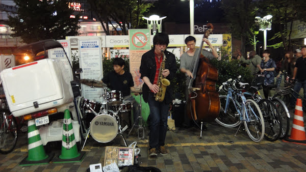 buskers play music on a corner of the sidewalk